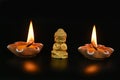 a little Buddha statue and burning candles on a black background Royalty Free Stock Photo