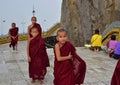 Little Buddhist Monks passing by with cheerful look at Golden Rock in Mon State, Myanmar