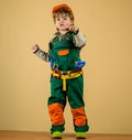 Little builder in helmet and tool belt pointing to you. Kid repairman in safety hard hat and overalls with toolbelt of Royalty Free Stock Photo