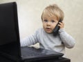 Little businessman sitting at the computer with a toy cell phone Royalty Free Stock Photo