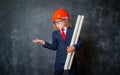 Little businessman in suit wearing safety red hard hat. time for check. Portrait of child makes hands gesture and Royalty Free Stock Photo