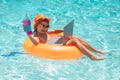 Little businessman working on tropical beach. Kid boy relaxing in the pool, using laptop computer in summer water. Child Royalty Free Stock Photo
