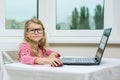 Little businesswoman. Child girl in adult glasses sits at table with computer Royalty Free Stock Photo