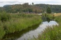 Little calm river with reflections in the vater and hill with forest in background