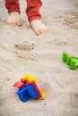 Little car, children toys and feet of little boy. Relax or playing on sand at beach. Summer and vacation time Royalty Free Stock Photo