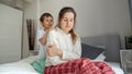 Little caring boy comforting and soothing her upset mother sitting on bed. Concept of loving family, parents and kids, love and Royalty Free Stock Photo