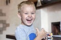 Little caucasian baby boy with blond hair and bright blue eyes laughs holding the car toy and showing thump up. Royalty Free Stock Photo