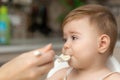 Little Caucasian baby boy with hand close his mouth no eat his food. Kid with dirty messy face sitting in high chair Royalty Free Stock Photo