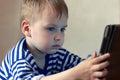 Little caucasian baby boy uses a tablet, seeing to the screen. Children time spending, computerization of youngsters. Royalty Free Stock Photo