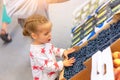 Little Caucasian beautiful girl is very surprised when choosing berries in a large store. Cute child is looking at blueberries Royalty Free Stock Photo