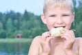 Little Caucasian blonde boy eating an pear on a hot summer day at the beach.