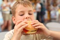 Little caucasian boy eating burger