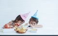 Little Caucasian boy and girl looking with suspicion at ingredient of birthday cake while two cute kids eat cake together Royalty Free Stock Photo