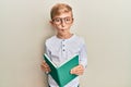 Little caucasian boy kid reading a book wearing glasses making fish face with mouth and squinting eyes, crazy and comical Royalty Free Stock Photo