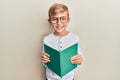 Little caucasian boy kid reading a book wearing glasses smiling with a happy and cool smile on face Royalty Free Stock Photo