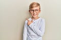 Little caucasian boy kid wearing casual clothes and glasses smiling cheerful pointing with hand and finger up to the side