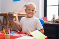 Little caucasian boy painting at the school screaming proud, celebrating victory and success very excited with raised arm Royalty Free Stock Photo