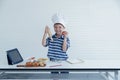 A little Caucasian boy with tablet to prepare food for cooking in studio kitchen Royalty Free Stock Photo