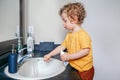 Little Caucasian boy toddler brushing teeth in bathroom at home. Health hygiene and morning routine for children. Cute funny child Royalty Free Stock Photo