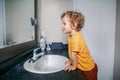 Little Caucasian boy toddler washing hands in bathroom at home. Health hygiene, morning routine for children. Cute funny child Royalty Free Stock Photo