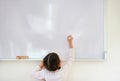 Little caucasian child girl writing something on whiteboard with a marker in the classroom. White board with copy space for text. Royalty Free Stock Photo