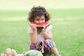 Little Caucasian cute girl holding sliced watermelon and enjoy eating or biting while picnic at park. Happy healthy child sitting Royalty Free Stock Photo