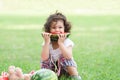 Little Caucasian cute girl holding sliced watermelon and enjoy eating or biting while picnic at park. Happy healthy child sitting Royalty Free Stock Photo
