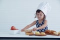 A little Caucasian girl chef holding rolling-pin and preparing the dough on the table at home kitchen Royalty Free Stock Photo