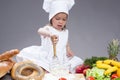 Little Caucasian Girl In Cook Uniform Making a Mix of Flour, Eggs and Vegetables With Whisk In Studio Royalty Free Stock Photo