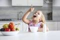 Little caucasian girl enjoing food sitting at table indoors. Child have a meal. Organic breakfast, healthy nutrition concept. Kid Royalty Free Stock Photo