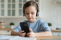 Little Caucasian girl in headphones use smartphone Royalty Free Stock Photo