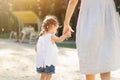 Little Caucasian girl holding her mother by the hand for a walk in a summer park. Strong family and love of children and parents Royalty Free Stock Photo