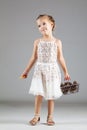 Little caucasian girl holding tiny shopping cart with pinecones