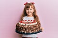 Little caucasian girl kid celebrating birthday holding big chocolate cake smiling with a happy and cool smile on face Royalty Free Stock Photo