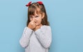 Little caucasian girl kid wearing casual clothes smelling something stinky and disgusting, intolerable smell, holding breath with Royalty Free Stock Photo