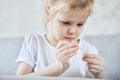 Little Caucasian girl learns to insert a thread into a needle. Royalty Free Stock Photo