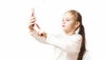 Little caucasian girl makes a selfie photo on a smartphone. Modern wireless technologies and devices concept. white background.