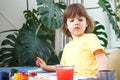 Little caucasian girl paints small toy figures in home interior. A cute three year old child is engaged in creativity Royalty Free Stock Photo