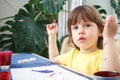 Little caucasian girl paints small toy figures in home interior. A cute three year old child is engaged in creativity Royalty Free Stock Photo