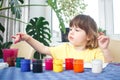 Little caucasian girl paints small toy figures in home interior. A cute three year old child is engaged in creativity Royalty Free Stock Photo