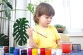 Little caucasian girl paints small toy figures in home interior. A cute three year old child is engaged in creativity Royalty Free Stock Photo