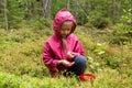 Little caucasian girl is picking wild berries in autumn forest Royalty Free Stock Photo