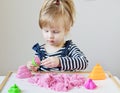 Little Caucasian Girl Playing with Pink Kinetic Sand at Home