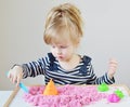 Little Caucasian Girl Playing with Pink Kinetic Sand at Home