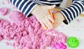 Little Caucasian Girl Playing with Pink Kinetic Sand at Home