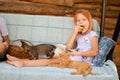 A little caucasian girl of six years old is sitting on a garden swing, playing with kittens and eating green apples. Happy