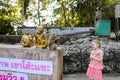 Little caucasian girl standing near monkey golden statuettes and macaco at zoo in Thailand.
