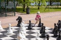 Little caucasian girl wearing a straw hat plays giant chess outdoors Royalty Free Stock Photo