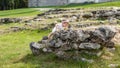 Little Caucasian girl in a white airy dress walking climbs on old ruins stones. Beautiful elegant child walking on a meadow Royalty Free Stock Photo