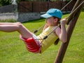 Little caucasian girl, young school age child sitting on a swing, side view, closeup, portrait. Having fun outdoors alone, playing Royalty Free Stock Photo